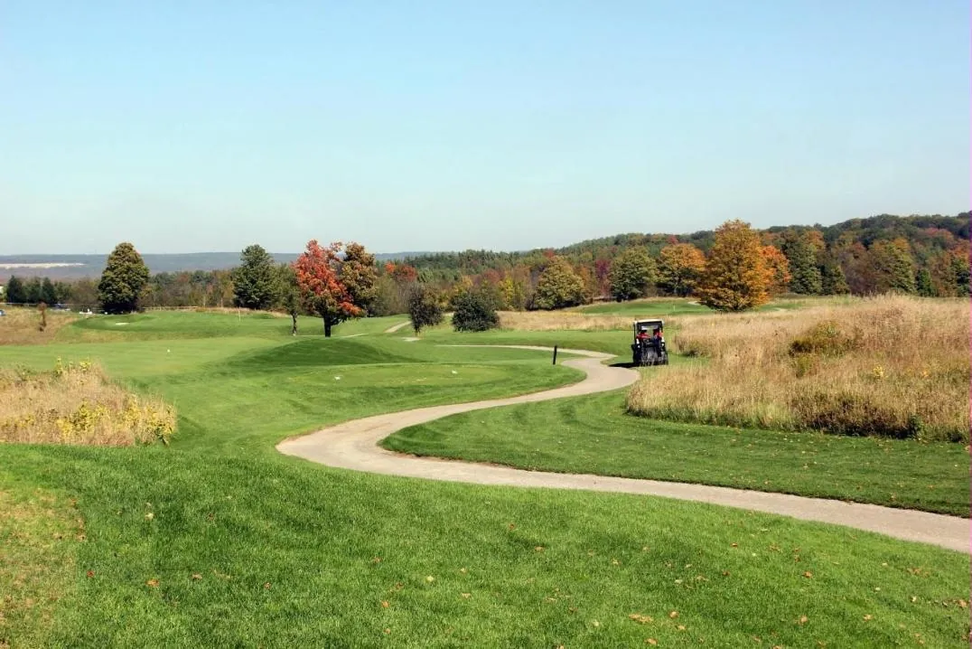 A golf cart on a winding path through fall colours at Tangle Creek during the charity tournament